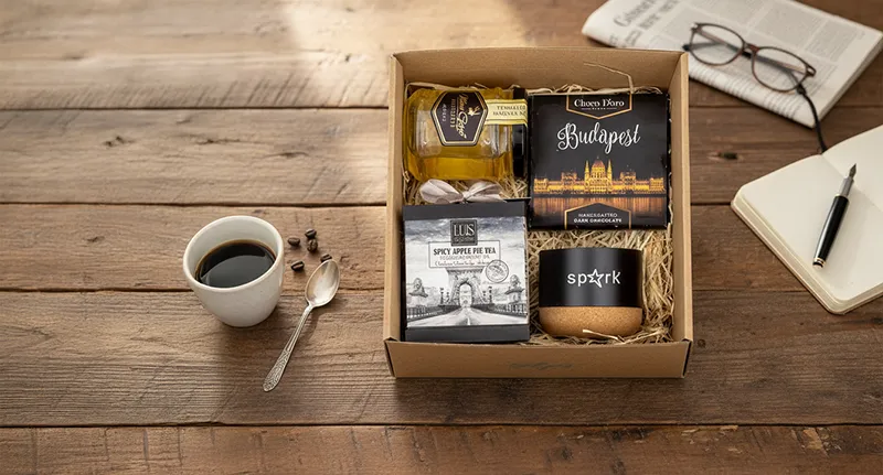 Fűszeres almáspite tea díszdobozban 60g, Akácméz 250g, Choco D'oro Budapest táblacsokoládé 80g, Környezetbarát hangszóró újrahasznosított alumíniumból, parafa alappal, bluetooth funkcióval, 300 mAh akkumulátorral.